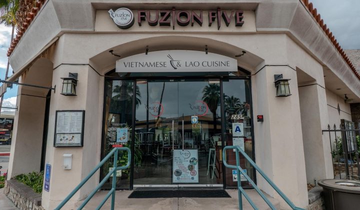 Exterior of Fuzion Five restaurant, featuring Vietnamese and Lao cuisine. The entrance has glass doors and a few stairs leading up from the sidewalk.