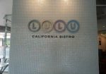 Wall with "LULU California Bistro" logo consisting of four circles with letters inside above the text.