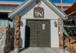 Entrance of a building with double doors, flanked by two carved wooden tiki statues.