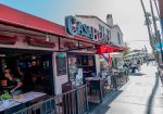 Outdoor view of Casa Blanca restaurant with a red awning, open interior, people dining, and a busy sidewalk in a sunny street setting.