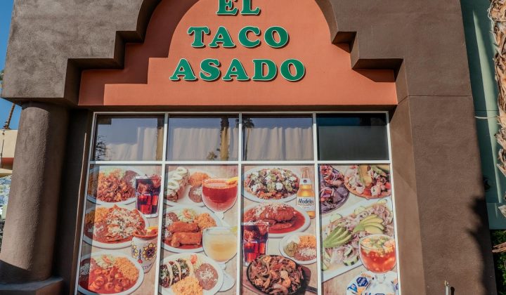 Restaurant storefront with "El Taco Asado" sign above large windows displaying images of various Mexican dishes, drinks, and ingredients.