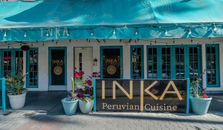 Front exterior of a Peruvian restaurant named INKA, with a turquoise awning, string lights, and potted plants along the entrance.
