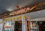 Entrance of La Bonita's Mexican Restaurant, featuring a wooden sign with yellow and red lettering, a glass door, and string lights above.