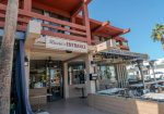 Exterior view of a restaurant named Riccio's with outdoor seating, a sign for seafood, steak, and pasta, and palm trees nearby.