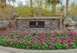 Stone sign with "The Ritz-Carlton" logo, surrounded by pink flowers and greenery.