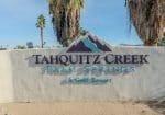 Sign for Tahquitz Creek Palm Springs Golf Resort, featuring mountain design and surrounded by palm trees.