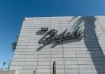 The image shows a building exterior with the sign "The Skylark" on a tiled wall. A security camera is mounted on the top left corner. A cactus is visible below. Sky is clear and blue.