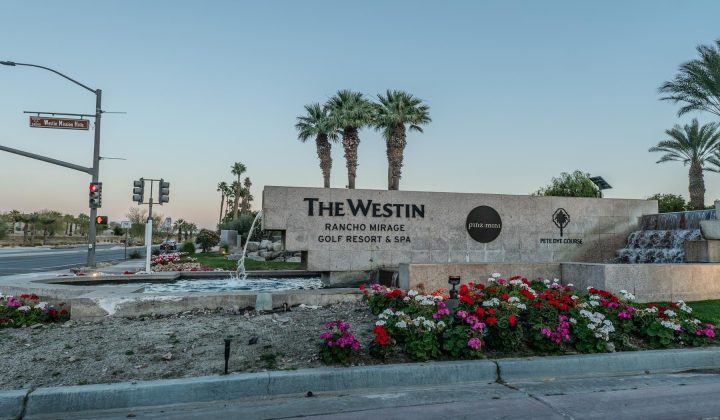 Entrance sign for The Westin Rancho Mirage Golf Resort & Spa, featuring landscaping with flowers and palm trees.