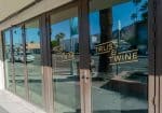 Glass doors with "Truss & Twine" logo reflect a sunny street scene with palm trees and cars.