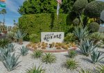 Sign reading "Villa Royale" surrounded by desert landscaping with cacti and succulents, against a backdrop of trees and a road sign.