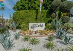 Entrance sign for Villa Royale surrounded by desert plants, including agave and cacti, under a clear blue sky.