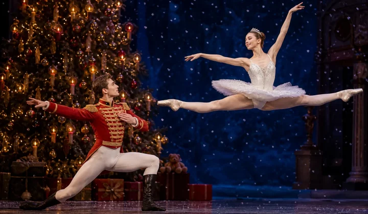 Nutcracker prince and ballerina on stage with a lit Christmas tree